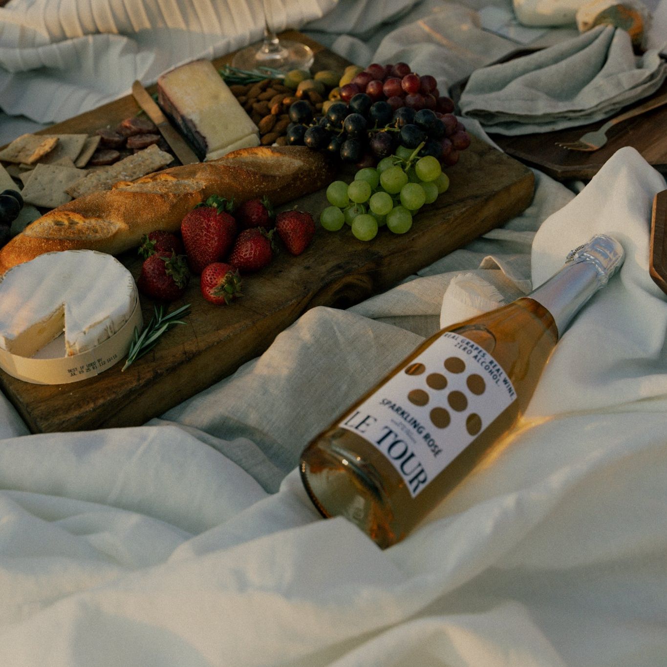 bottle-of-le-tour-non-alcoholic-sparkling-wine-with-charcuterie-board-on-picnic-blanket