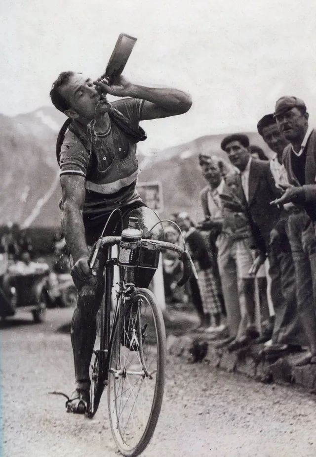 vintage-black-and-white-photograph-of-cyclist-drinking-from-bottle-on-bicycle